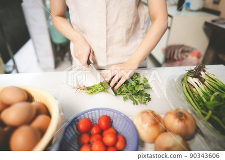 Woman hand using knife prepared cutting coriander at home. 90343606