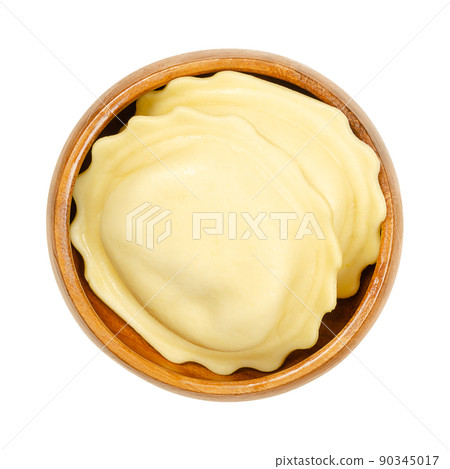 Big filled dumplings in a wooden bowl. Uncooked, stuffed egg pasta, filling wrapped in thin batter, ready to boil, steam or to fry. Close-up from above, isolated on white background, macro food photo. Big filled dumplings in a wooden bowl. Uncooked, stuffed egg pasta, filling wrapped in thin batter, ready to boil, steam or to fry. Close-up from above, isolated on white background, macro food photo. 90345017