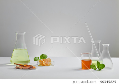 Honey and turmeric decorated with transparent podium and beaker test tube with blank space in white laboratory background for experiment advertising , front view Honey and turmeric decorated with transparent podium and beaker test tube with blank space in white laboratory background for experiment advertising , front view 90345825
