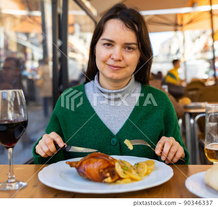 Female tourist tasting Toston asado in restaurant of Salamanca 90346337