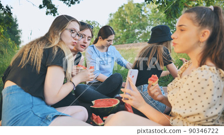 Friends have fun eating watermelon outside the city at a picnic. Friends have fun eating watermelon outside the city at a picnic. 90346722