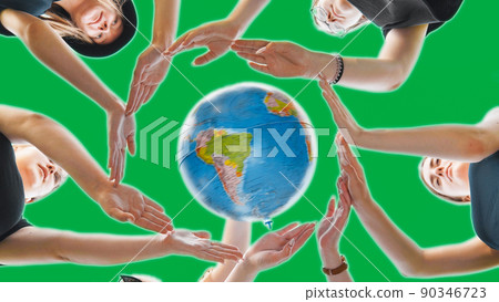 Schoolgirls hug the earth globe with their hands, making a circle out of them on a green background. Schoolgirls hug the earth globe with their hands, making a circle out of them on a green background. 90346723