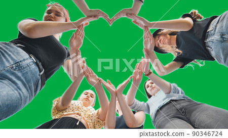 Girlfriends girls make a heart shape from their hands on a green background. 90346724
