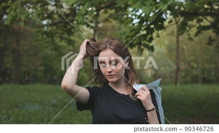 A girl poses by the forest on a warm summer evening. 90346726