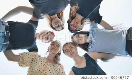 Happy girls girlfriends hugging in a circle on a background of blue sky. Happy girls girlfriends hugging in a circle on a background of blue sky. 90346727