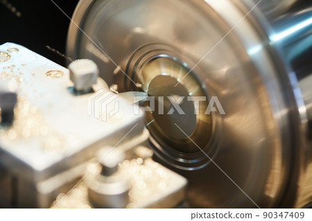 Close-up of rotating metal workpiece with cutting tool at production plant Close-up of rotating metal workpiece with cutting tool at production plant 90347409