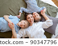Happy mother with two children laying on bed at home having fun and playing 90347796