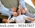Happy mother with two children laying on bed at home having fun and playing 90347807