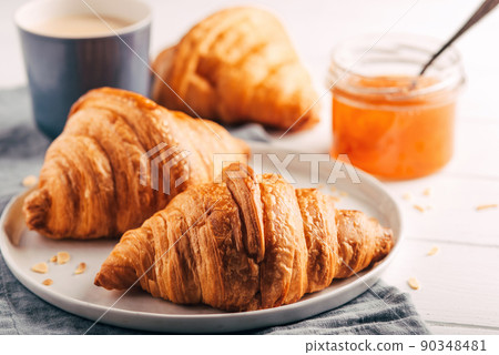 Plate with fresh croissants, jam and coffee on white wooden table. Close up. Plate with fresh croissants, jam and coffee on white wooden table. Close up. 90348481
