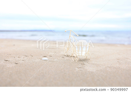 A three-wheeled bicycle on the beach and a transparent globe figurine 90349997