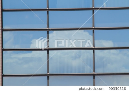 Blue sky and white clouds reflected in the windows of an office building 90350818