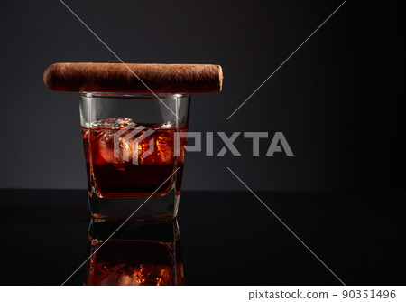Glass of whiskey with ice and cigar. Glass of whiskey with ice and cigar. 90351496