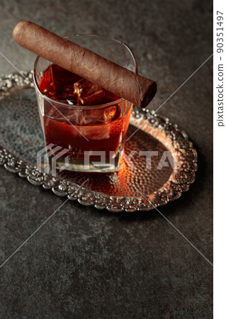 Whiskey with ice and cigar on an old stone table. Whiskey with ice and cigar on an old stone table. 90351497