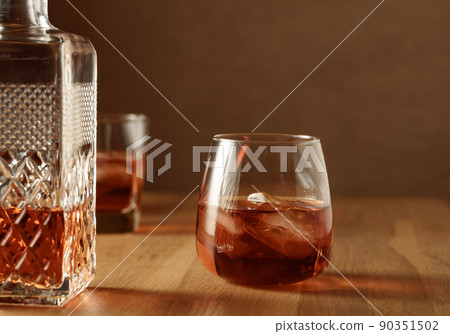 Whiskey with ice on an oak table. 90351502