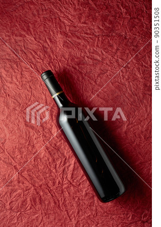 Bottle of red wine on a crumpled red paper background. Bottle of red wine on a crumpled red paper background. 90351508