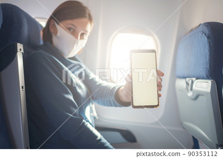 Young beautiful woman sitting at window of plane during the flight Young beautiful woman sitting at window of plane during the flight 90353112