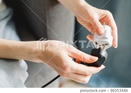 Woman applies universal travel adapter electrical plug converter power socket 90353486