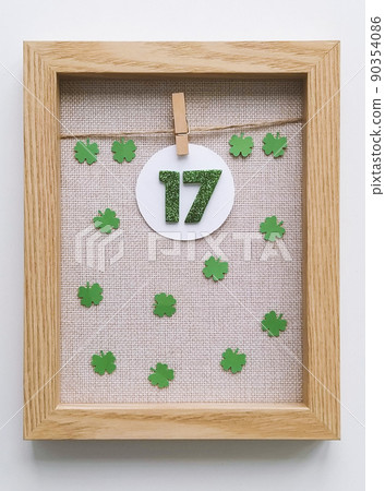 Wooden frame with miniature green numbers 17 with four-leaf clover on fabric background 90354086