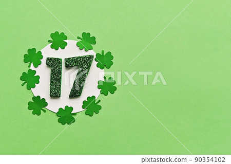 Numeral 17 on white background with frame of paper-cut four-leaf clover leaves 90354102