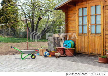 Small beautiful wooden house shed or storage hut for garden tools equipment and bicycles at backyard at beautiful american or european countryside backyard. Cozy rural yard stuff warehouse Small beautiful wooden house shed or storage hut for garden tools equipment and bicycles at backyard at beautiful american or european countryside backyard. Cozy rural yard stuff warehouse 90354117