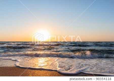 Scenic panoramic view of bright warm red orange dramatica sunrise or sunset at early morning over sand coast of ocean water surface. Beautiful seaside golden dusk panorama background on stormy sea 90354118