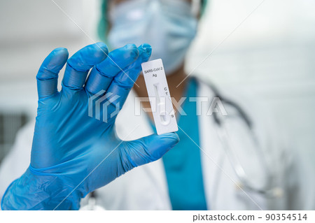 Asian doctor in PPE suit show positive test result with Saliva Antigen Test Kit for check Covid-19 coronavirus in hospital. 90354514