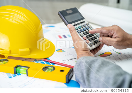 Asian engineer with architectural house plan project blueprint, graph and yellow helmet and engineering construction tools. Asian engineer with architectural house plan project blueprint, graph and yellow helmet and engineering construction tools. 90354515
