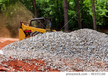 Excavation at a construction site, mini loader bobcat transports crushed stone to different construction Excavation at a construction site, mini loader bobcat transports crushed stone to different construction 90355180