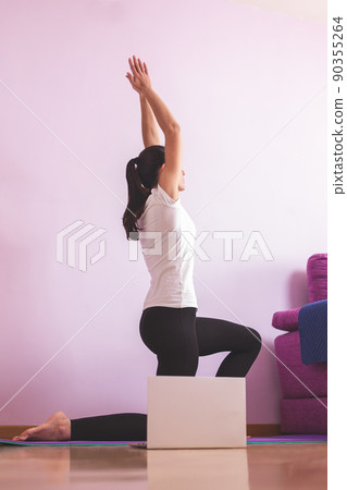 Young happy caucasian woman practicing yoga in the living room while looking at her laptop. Health care and wellness at home concept. 90355264