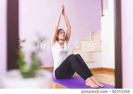 Young happy caucasian woman practicing yoga in the living room. Health care and wellness at home concept. Young happy caucasian woman practicing yoga in the living room. Health care and wellness at home concept. 90355266