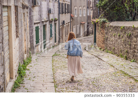 Woman tourist on background of Scenic panorama view of the historic town of Risan at famous Bay of Kotor on a beautiful sunny day with blue sky and clouds in summer, Montenegro, southern Europe Woman tourist on background of Scenic panorama view of the historic town of Risan at famous Bay of Kotor on a beautiful sunny day with blue sky and clouds in summer, Montenegro, southern Europe 90355333