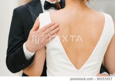 The groom gently and tenderly embraces the bride by the shoulders. Close-up of the hands of a happy couple 90355957