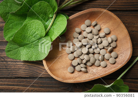 Burdock extract pills and leaves of arctium lappa - latin name for Burdock. Top view. Burdock extract pills and leaves of arctium lappa - latin name for Burdock. Top view. 90356081