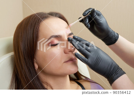 Pretty girl getting eyebrow waxing in beauty salon 90356412