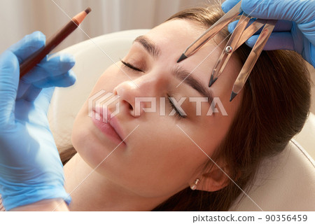 Cosmetologist measures the proportions of the eyebrows with the ruler. 90356459