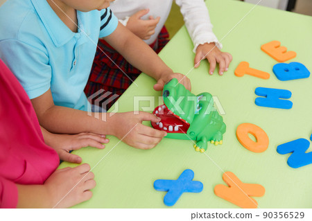 Preschool children playing with alphabet letters on a desk Preschool children playing with alphabet letters on a desk 90356529