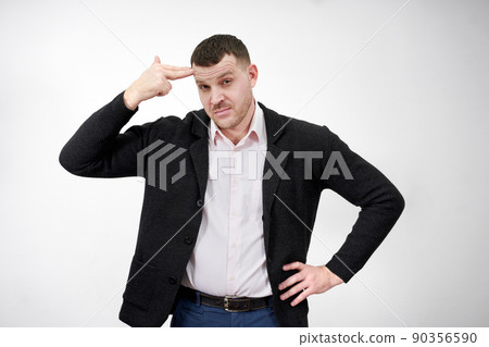 man pointing his finger to his head to shoot himself on a gray background, stress concept 90356590