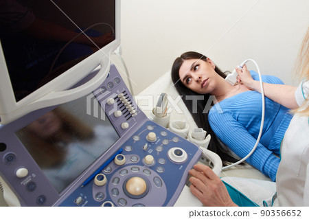 Doctor using ultrasound scanning machine examining female neck Doctor using ultrasound scanning machine examining female neck 90356652