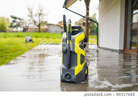 Pressure washer cleaning machine on wet concrete floor near the house build, cleaning terrace with a power washer 90357688