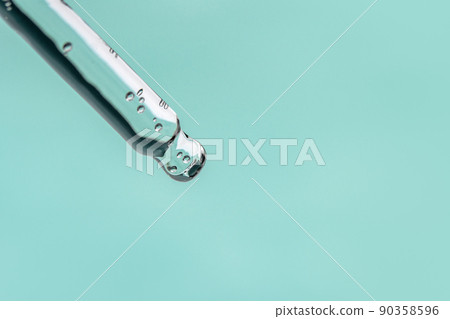 Closeup of pipette with serum, hyaluronic acid on blue background. Cosmetics and healthcare concept. Dose of essential oill, retinol with air bubbles. Beauty product presentation, front view, macro 90358596