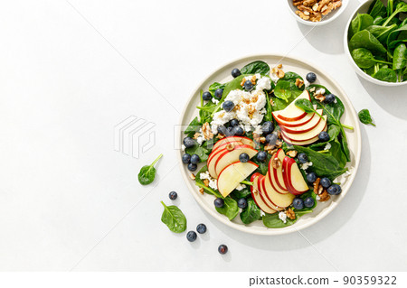 Apple and spinach fresh sweet fruit salad with blueberry, cheese cottage and walnuts, top view Apple and spinach fresh sweet fruit salad with blueberry, cheese cottage and walnuts, top view 90359322