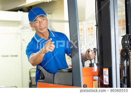在倉庫裡駕駛叉車的中年男工 90360553