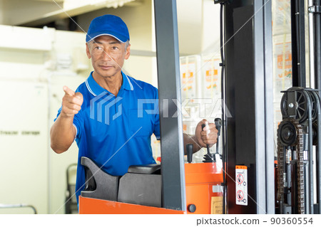 在倉庫裡駕駛叉車的中年男工 90360554