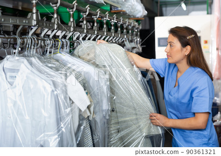Woman preparing garments for collection at dry-cleaning 90361321