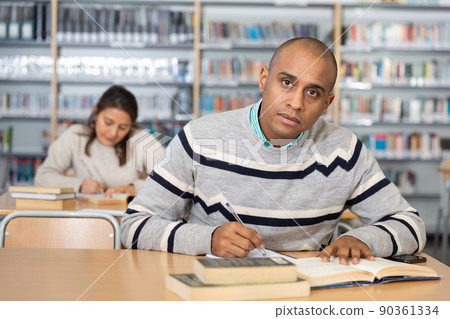 Young adult man studying in public library Young adult man studying in public library 90361334
