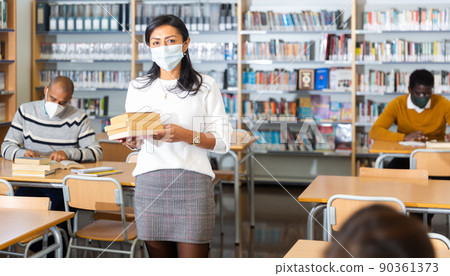 Adult latin american woman in protective mask visiting library Adult latin american woman in protective mask visiting library 90361373