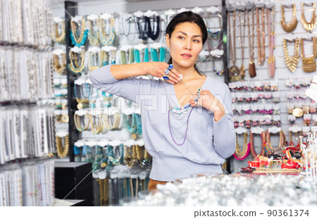 Interested asian woman choosing necklace in jewelry store 90361374