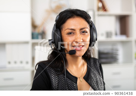 Friendly female call center operator receiving calls in office 90361438