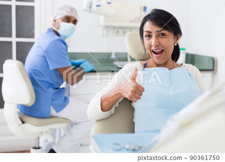 Portrait of satisfied woman visiting dentist giving thumbs up in dental clinic 90361750