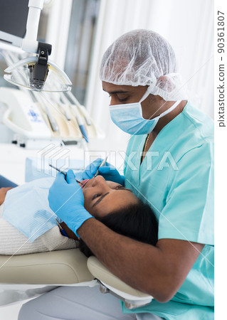 Professional dentist performing teeth treatment to woman in clinic Professional dentist performing teeth treatment to woman in clinic 90361807